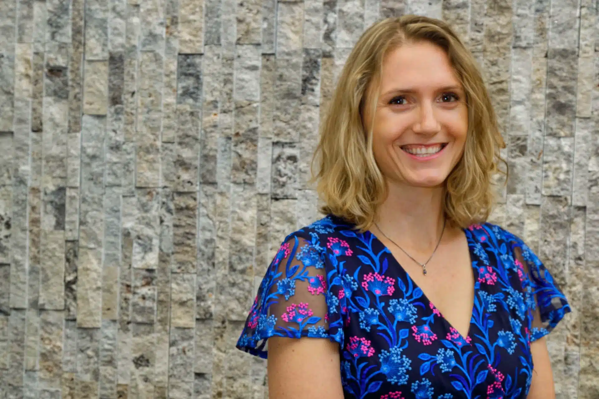 Amanda Hurfort portrait in front of gray rock wall-landscape orientation