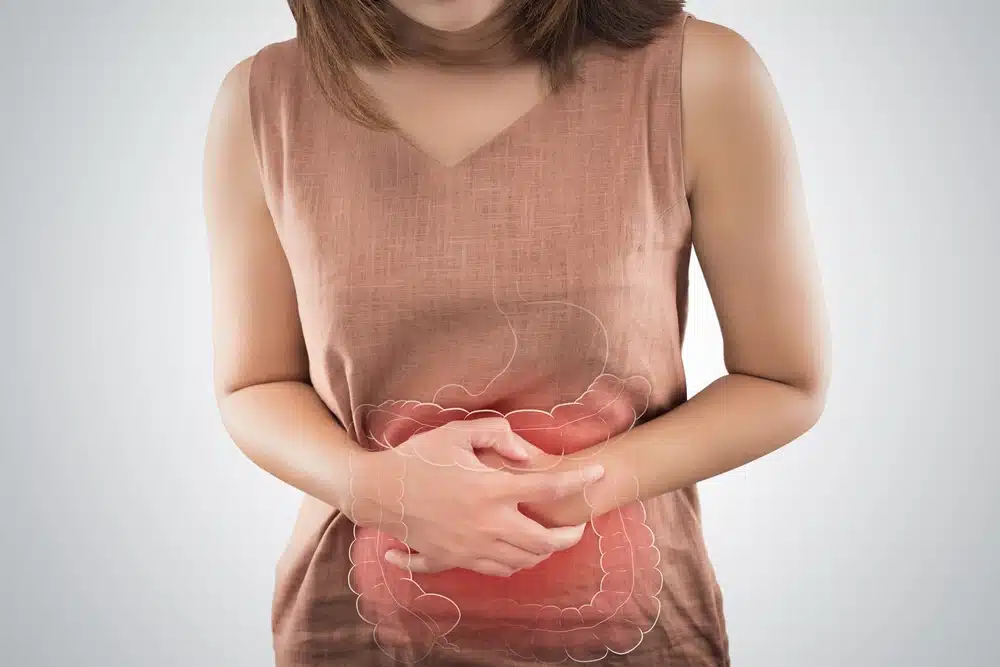 woman with hands grasping an intestinal outline over her shirt - gut health concept